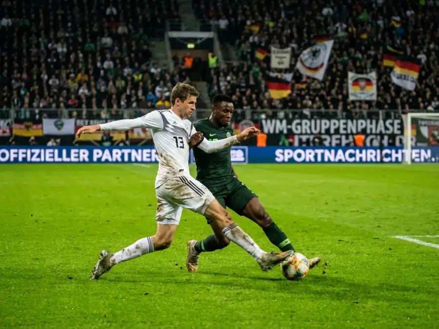 Zwei Fußballspieler im Zweikampf um den Ball während eines WM-Gruppenspiels vor vollen Rängen